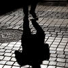 Shadow of a person walking on a cobblestone pavement in Lisbon