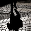 Shadow of a person walking on a cobblestone pavement in Lisbon Shadow of a person walking on a cobblestone pavement in Lisbon