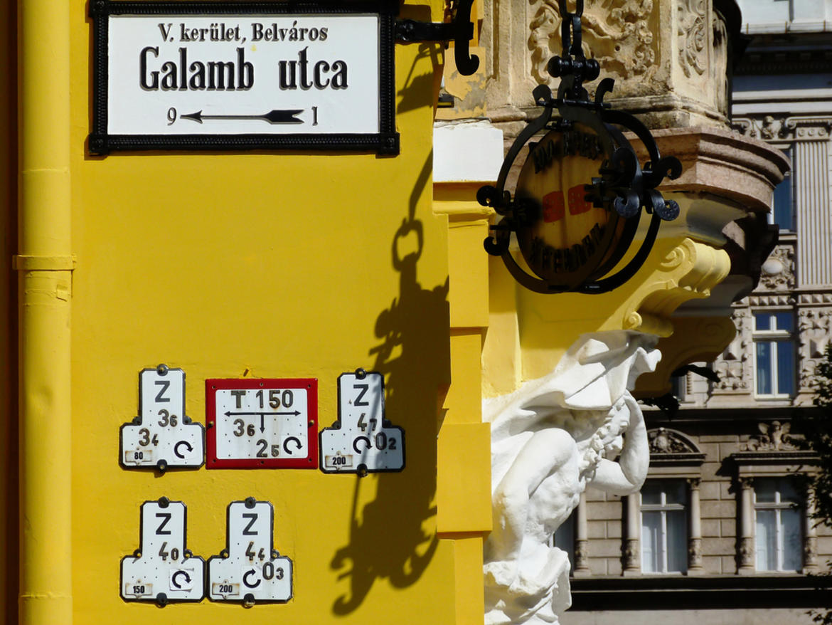 street name plate on a yellow wall