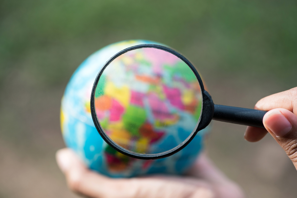 Hand holding an Earth globe and a magnifying glass 